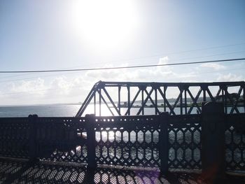 Silhouette bridge over sea against sky