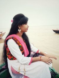 Woman looking away while sitting on shore