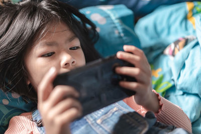 Girl using phone while relaxing on bed at home