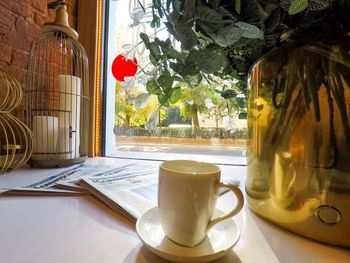 Coffee cup on table against window