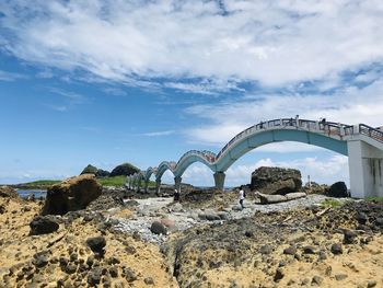 Arch bridge on rocks against sky