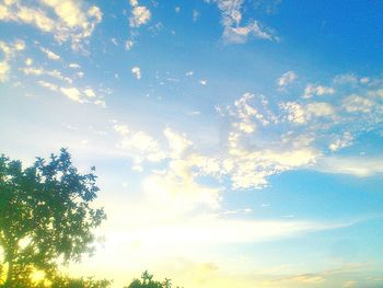 Low angle view of trees against cloudy sky