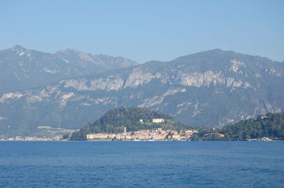 Scenic view of sea and mountains against clear blue sky