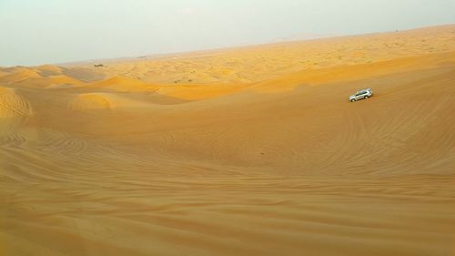 Car in desert against sky