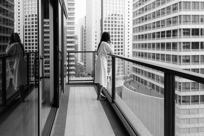 Rear view of woman standing by buildings in city