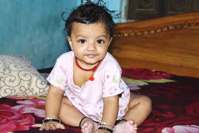 Portrait of cute baby boy lying on bed at home