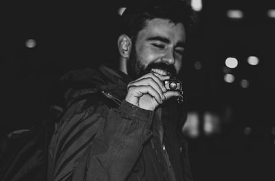 Portrait of young man holding camera at night