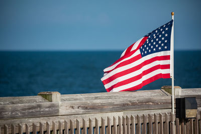 Flag by sea against blue sky