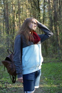 Young woman with long hair standing against trees at forest
