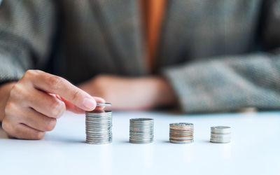 Midsection of man stacking coins on table