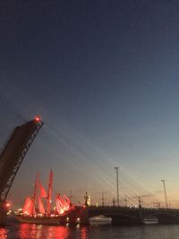 Cranes at harbor against sky at night