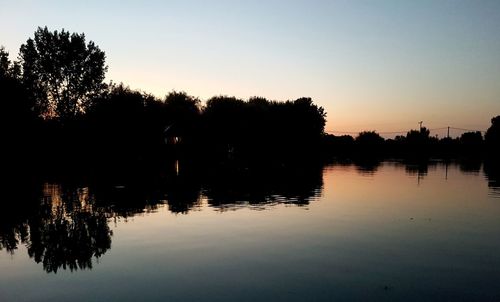 Silhouette trees by lake against sky during sunset