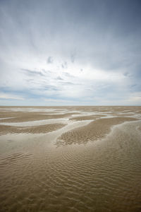 Sand, low tide with ripples and reflections.