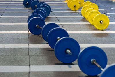 Groups of fitness barbells with blue and yellow disks