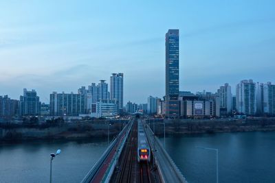 City by river and buildings against sky