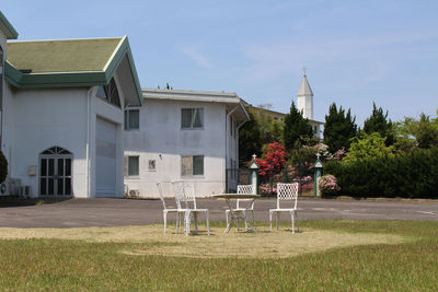 Houses on field by building against sky