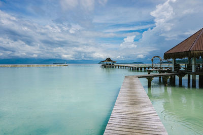 Pier over sea against cloudy sky