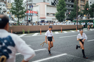 Rear view of people walking on road in city