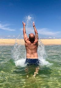 Man splashing water from sea against sky