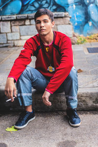 Portrait of young man looking away while sitting on seat