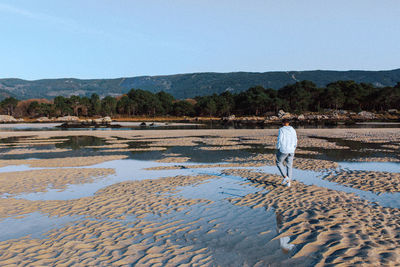 Rear view of man standing on puddle