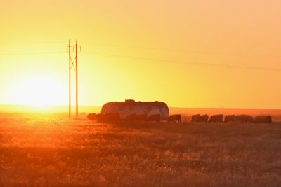 Hay bales on field against sky during sunset