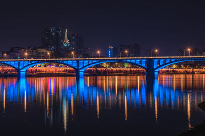 Illuminated bridge over river at night