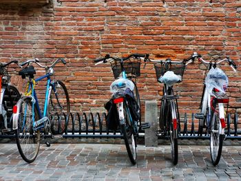 Bicycles on sidewalk against brick wall
