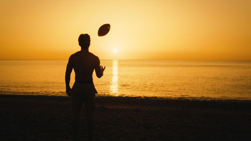 Silhouette of a man at sunset with american football ball