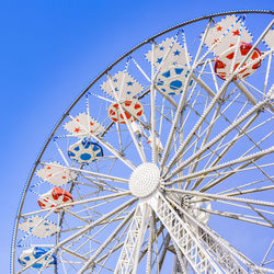 Low angle view of ferris wheel against clear blue sky