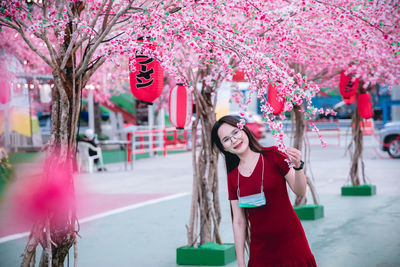 Woman standing by pink cherry blossom tree