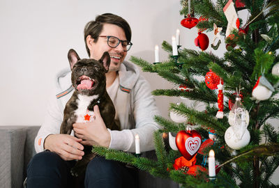 Owner and french bulldog laughing by christmas tree