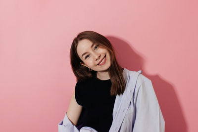Portrait of a smiling young woman against wall