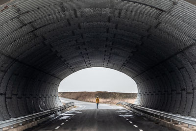 Full length of woman standing on road under tunnel