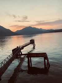 Pier on lake against sky during sunset