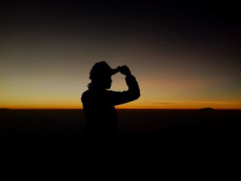 Silhouette woman standing against sky during sunset