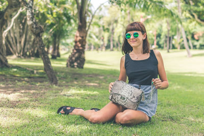 Woman wearing sunglasses sitting on field