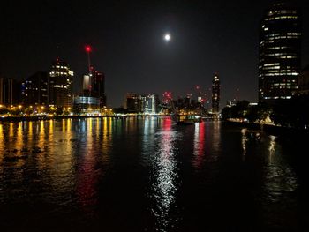 Illuminated buildings at waterfront at night