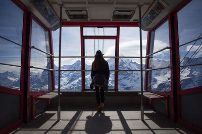 Rear view of women looking towards snowcapped mountains through ski lift windows