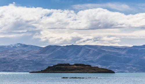 Scenic view of sea by mountains against sky