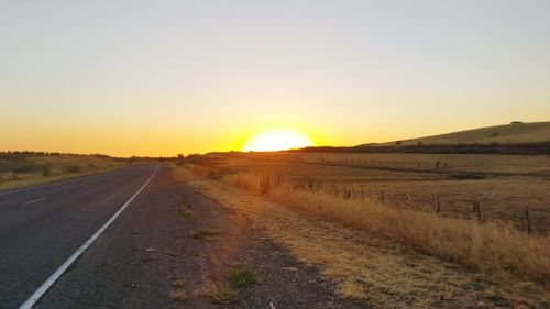 Road amidst landscape against clear sky during sunset