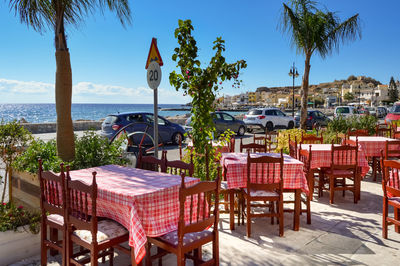 Chairs and tables at restaurant by sea against clear sky