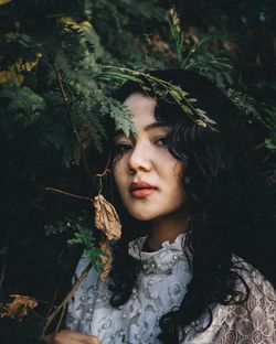 Portrait of beautiful young woman against plants