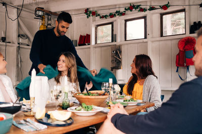 Young man covering female friend with blanket during lunch party