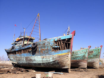 Abandoned boats against blue sky