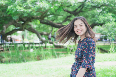 Portrait of smiling young woman against trees