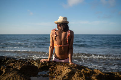 Rear view of woman on beach against sky