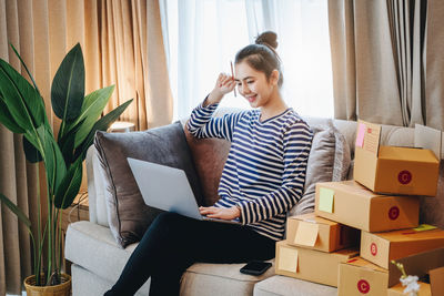 Young woman using laptop while sitting on sofa at home