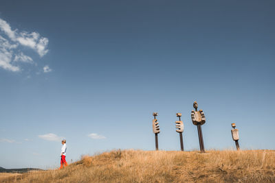 Rear view of woman walking on field against sky