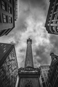 Low angle view of skyscrapers against cloudy sky